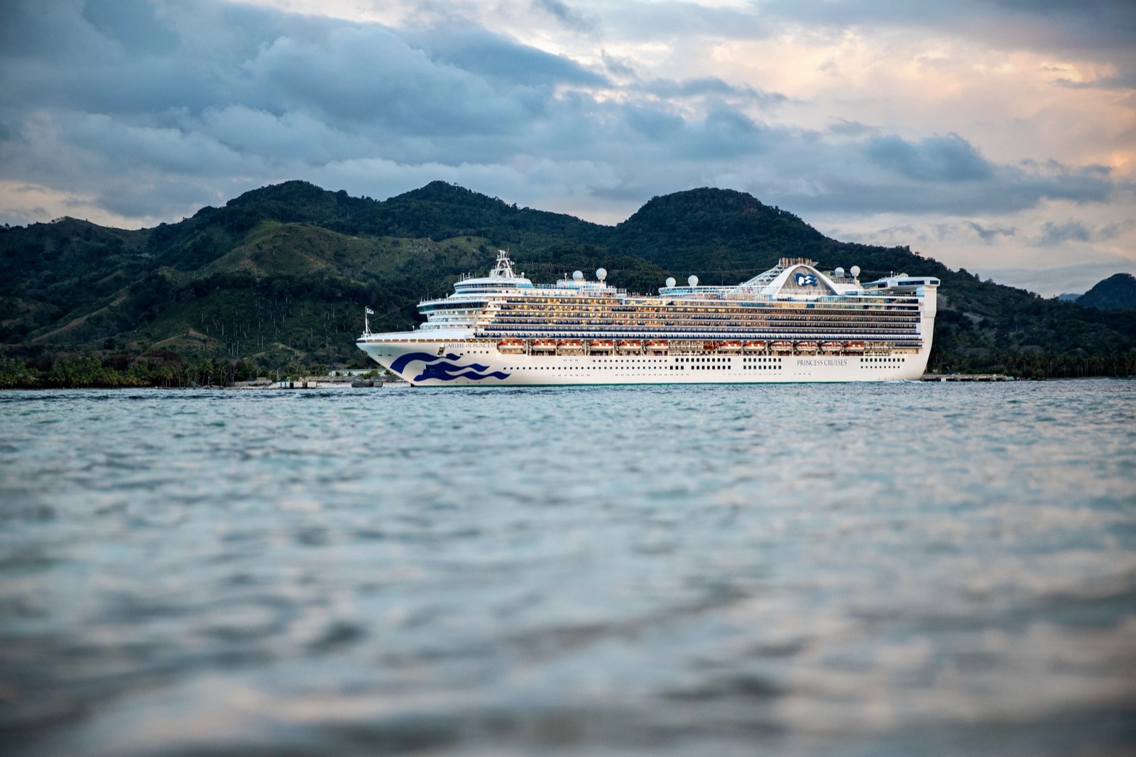The cruise ship Caribbean Princess docked below green hills at Amber Cove in the Dominican Republic