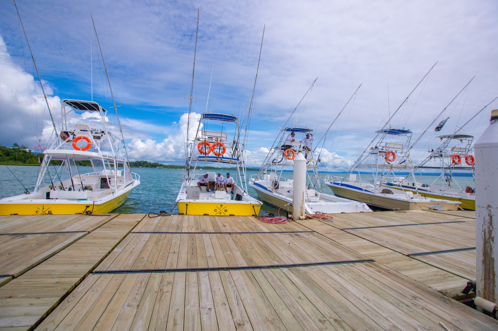 Crocodile Bay's yellow-hulled sportfishing boats tied up along the resort's wooden dock in Puerto Jiménez, with captains on board