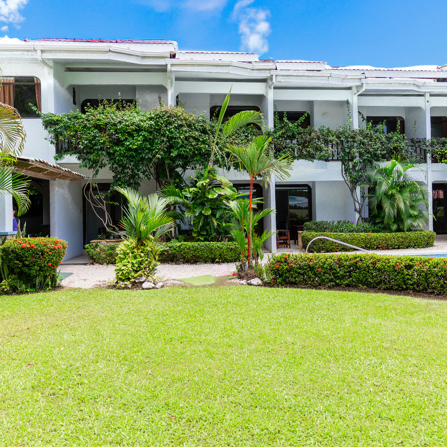 Hotel Giada's two-storey guest rooms behind a lawn and tropical garden in Sámara