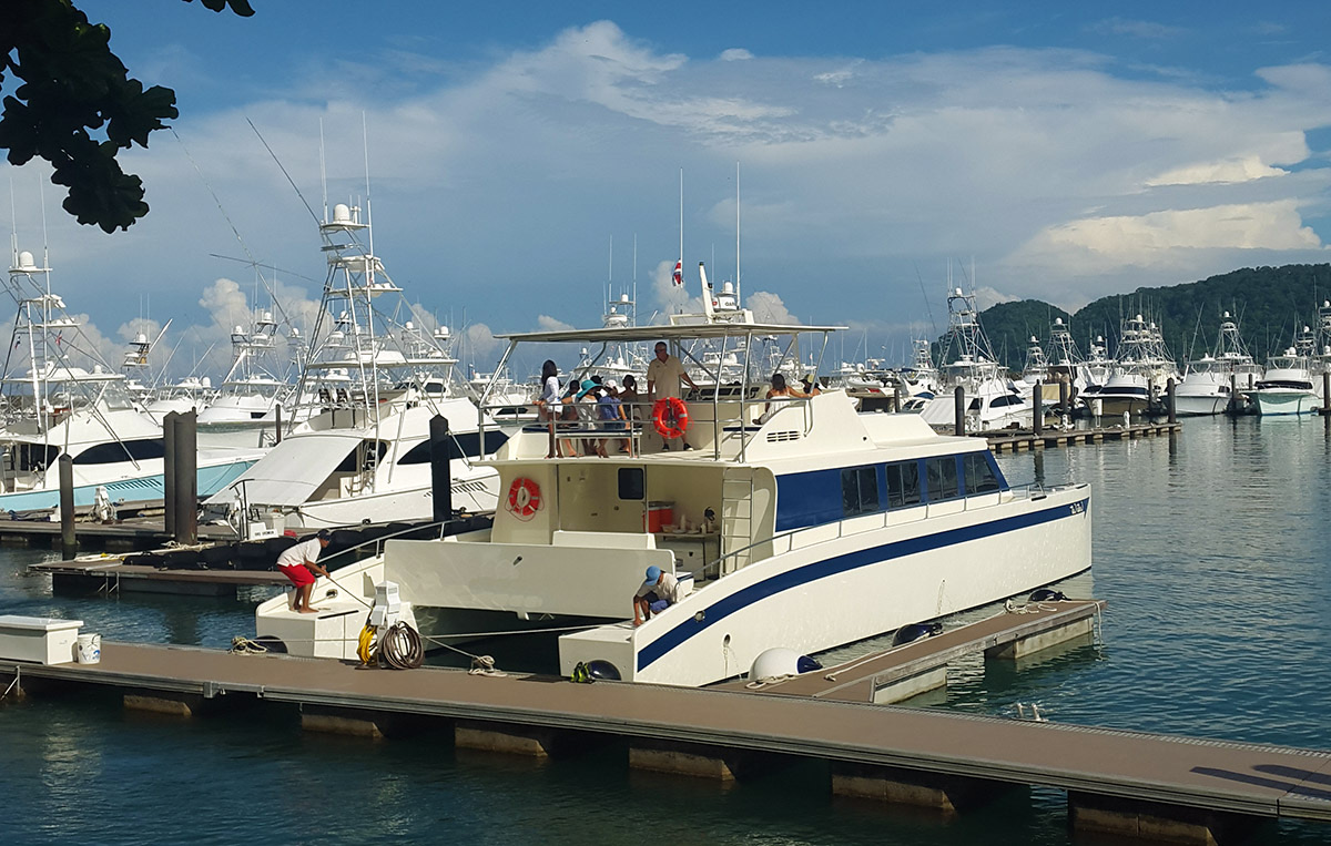 The Adventure Tours Costa Rica Tortuga Island catamaran tied up at Los Sueños Marina, with sportfishing boats in the slips behind